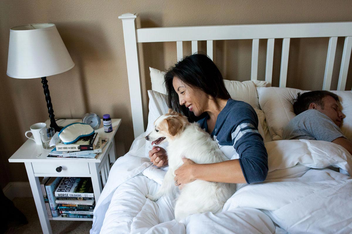 Woman waking up, cuddling dog